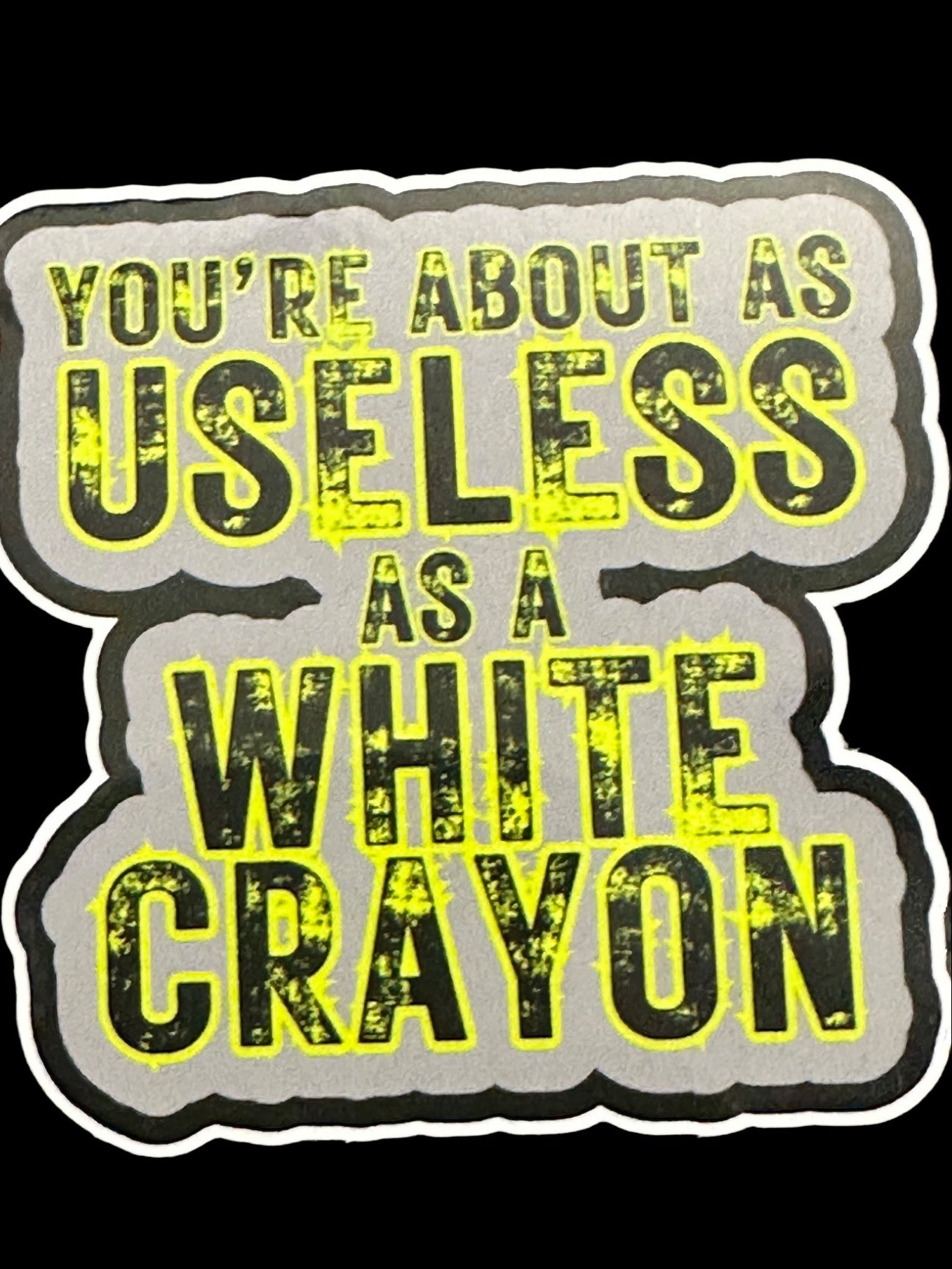 Sticker with text 'You're about as useless as a white crayon' on a black background